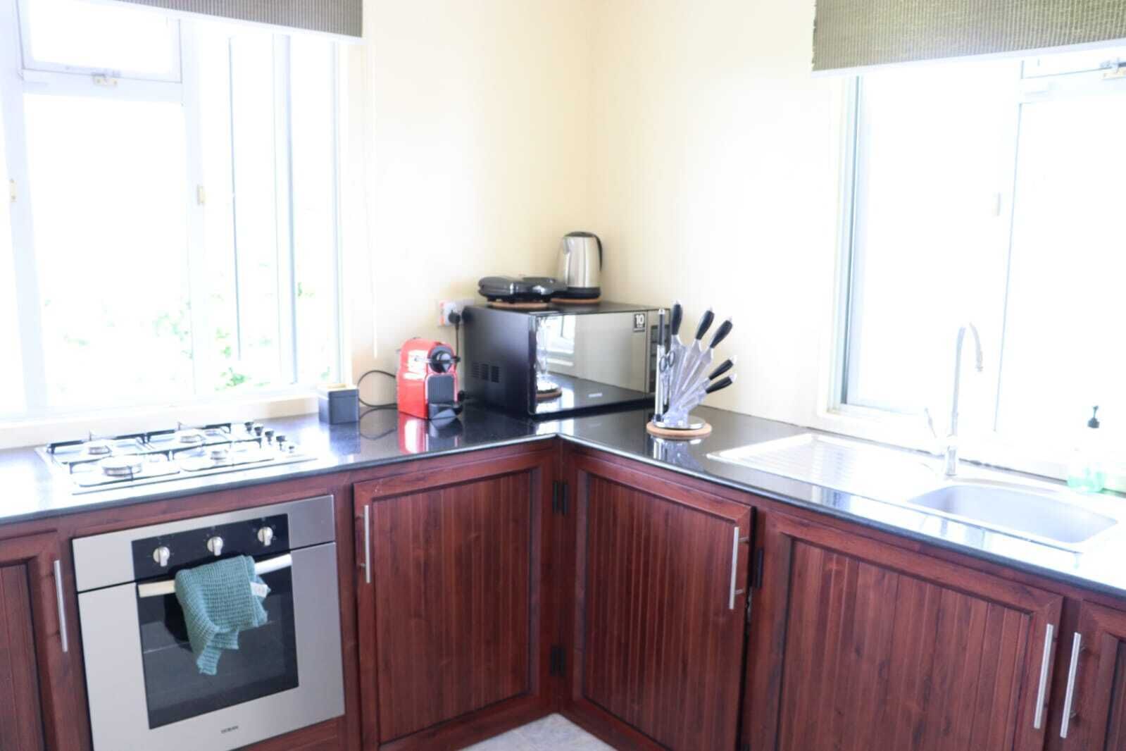 Een keuken met houten kastjes, een gasfornuis, een broodrooster en een spoelbak.