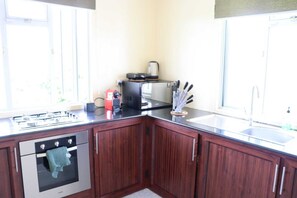 Une cuisine avec des meubles de rangement en bois, une cuisinière à gaz, un grille-pain et un évier.