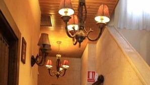 A hallway with hexagonal patterned tiles, wooden doors, and wall-mounted sconces. - Hotel Doña Isabel (Elche)