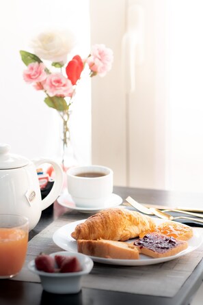 Een ontbijtsetting met een croissant, jam en een kop koffie op een tafel.