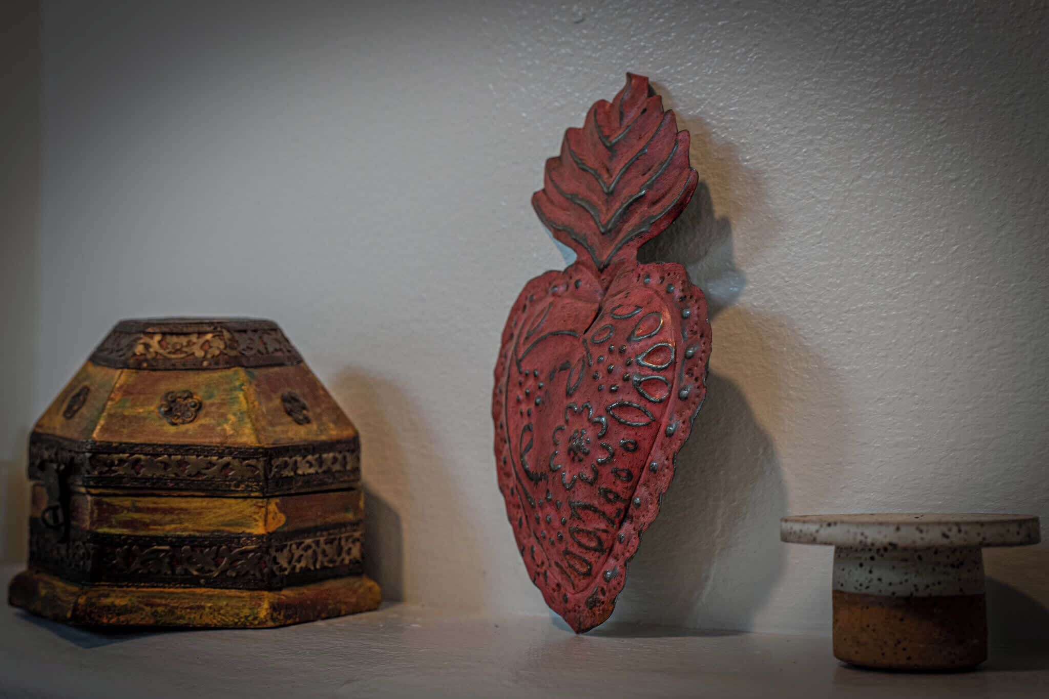 Un cofre de madera con intrincados grabados y un objeto con forma de hoja decorativa a su lado.