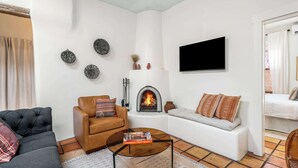 A living room with a fireplace, a TV mounted on the wall, and a sofa. - Steps to the Plaza and Georgia O'Keeffe Museum (Santa Fe)
