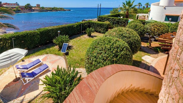 Une propriété située sur la côte, dotée d’une piscine, de chaises longues et offrant une vue sur la mer.