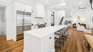 A spacious kitchen with white cabinetry, a large island, and a wooden floor. - Gulf Getaway with Private Pool and LSV (Santa Rosa Beach)