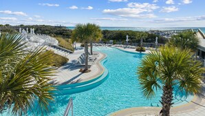A pool with a curved design, surrounded by palm trees and lounge chairs, with a view of the ocean and a clear sky. - Gulf Getaway with Private Pool and LSV (Santa Rosa Beach)