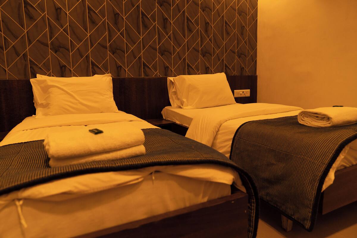 A hotel room with two beds, each with a headboard, and a wall with a geometric pattern.