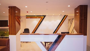 A reception desk with a modern design, featuring geometric patterns and wood accents. - The Flamboyant Natraj (Bharuch)