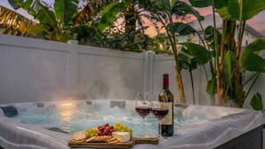 Un bain à remous avec une planche en bois remplie de collations et deux verres de vin rouge.