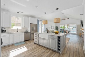 Une cuisine moderne avec des meubles blancs, un îlot central et un coin repas offrant une vue agréable.