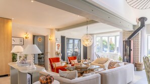 Ein modernes Wohnzimmer mit einer Sofagarnitur, einem Couchtisch und einem Essbereich mit einer Lampe.