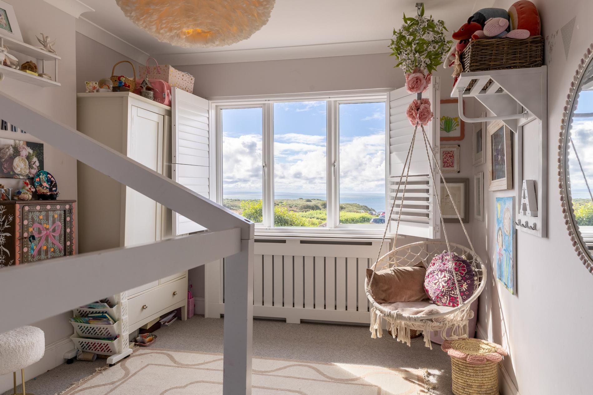 A room with a large window, a hanging chair, and a white radiator.