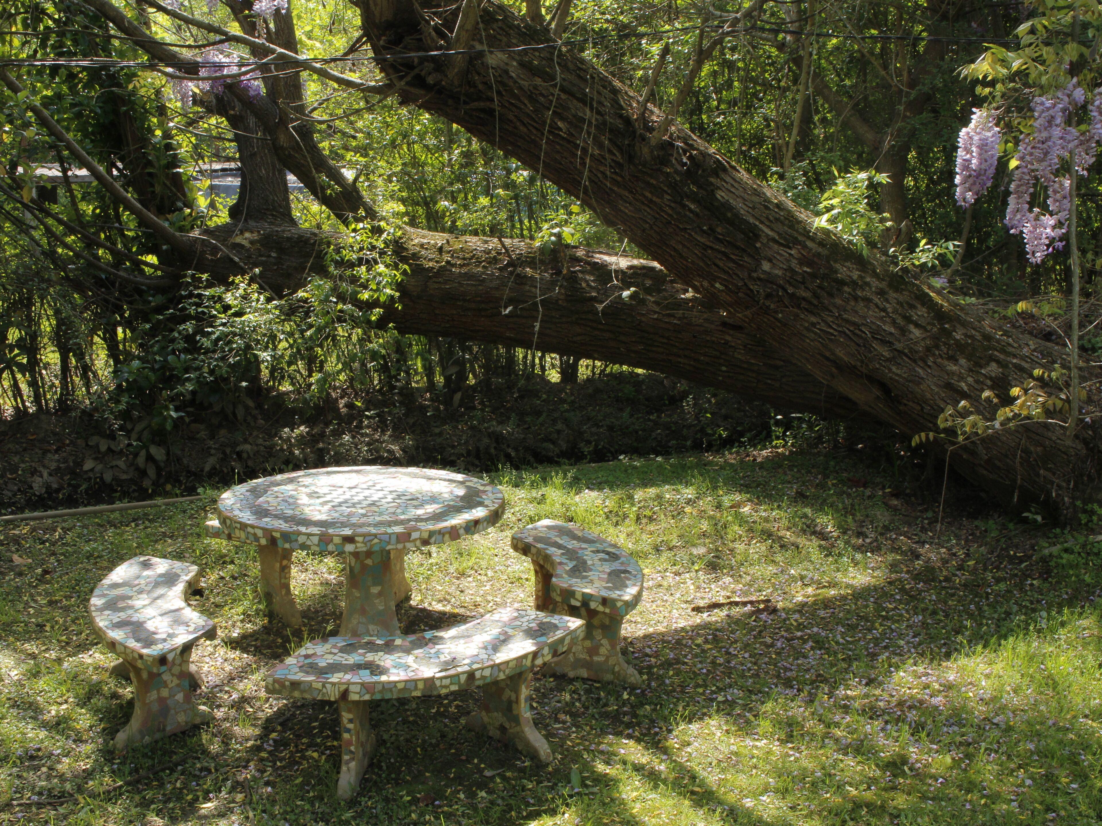 Uma mesa redonda com bancos de mosaicos num jardim.