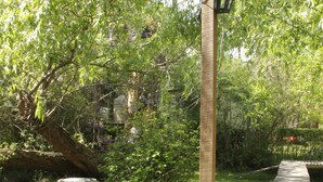 Ein hölzerner Weg schlängelt sich durch einen Garten mit einer Laterne und Steinsitzen.