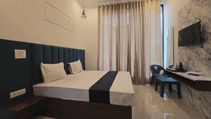Una habitación de hotel moderna con una cama grande, un escritorio, una silla y un televisor en la pared.