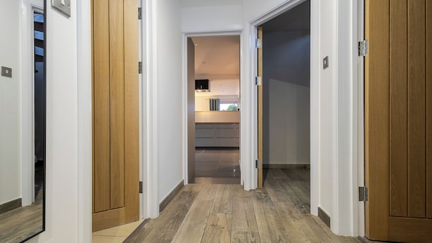 Un couloir avec des portes en bois et, au fond, une cuisine.