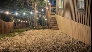 Una casa con fachada de madera, camino de grava y luces colgantes.