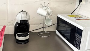 Una cocina con cafetera, microondas y hervidor sobre una encimera.