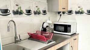 Una cocina moderna con microondas, pileta y una cesta roja en la encimera.