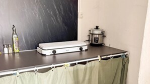 Una cocina con estufa a gas portátil, una olla de cocción lenta y una pequeña mesa con saleros y pimenteros.