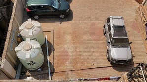 Vista aérea de um estacionamento com dois carros e dois tanques de água grandes.