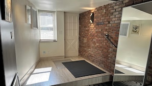 A modern room with a brick wall, a door, a small window with blinds, and a black and white patterned rug. - Prospect Park Escape (Brooklyn)