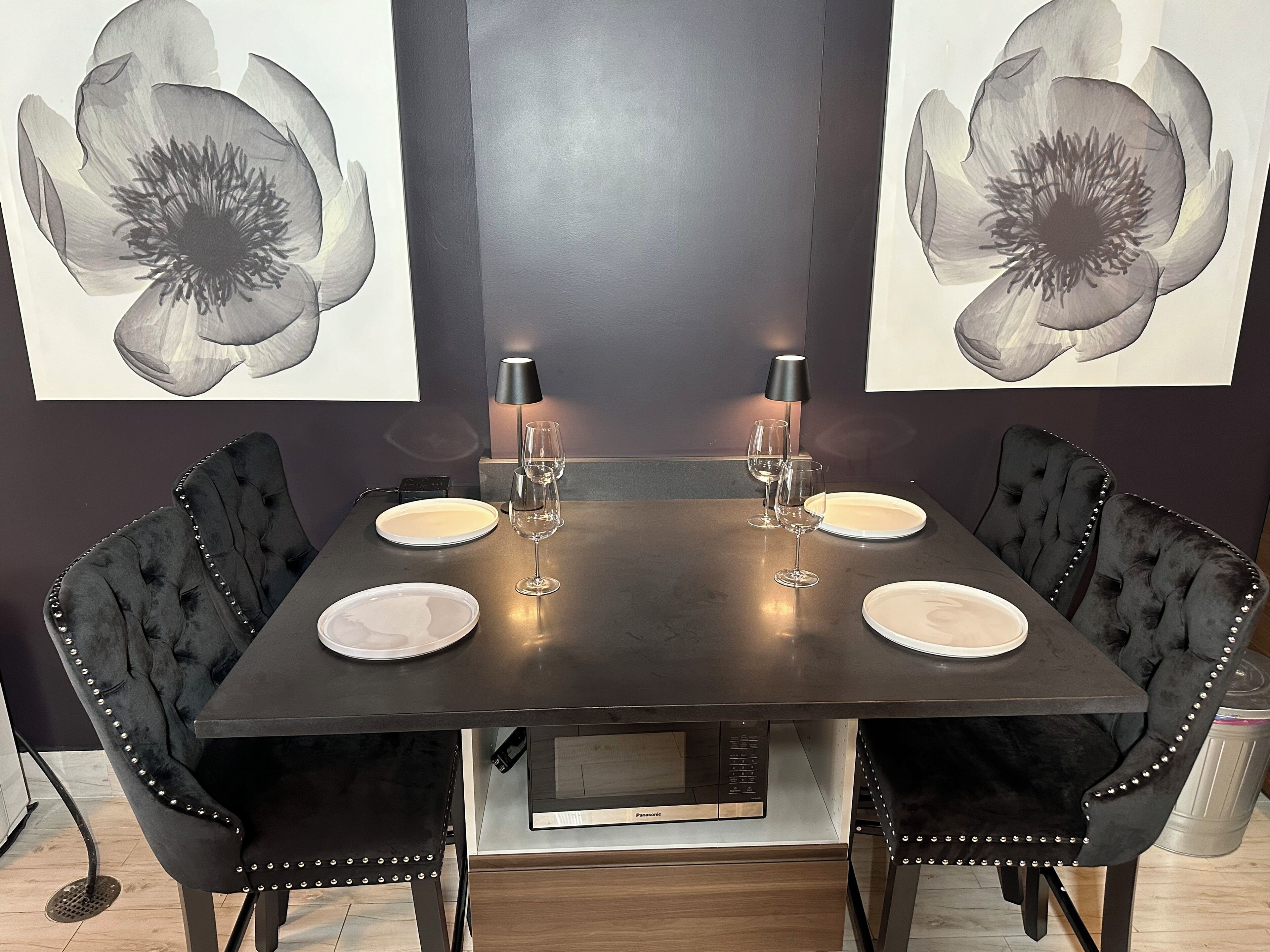 A dining table with four chairs, two lamps, and two plates.