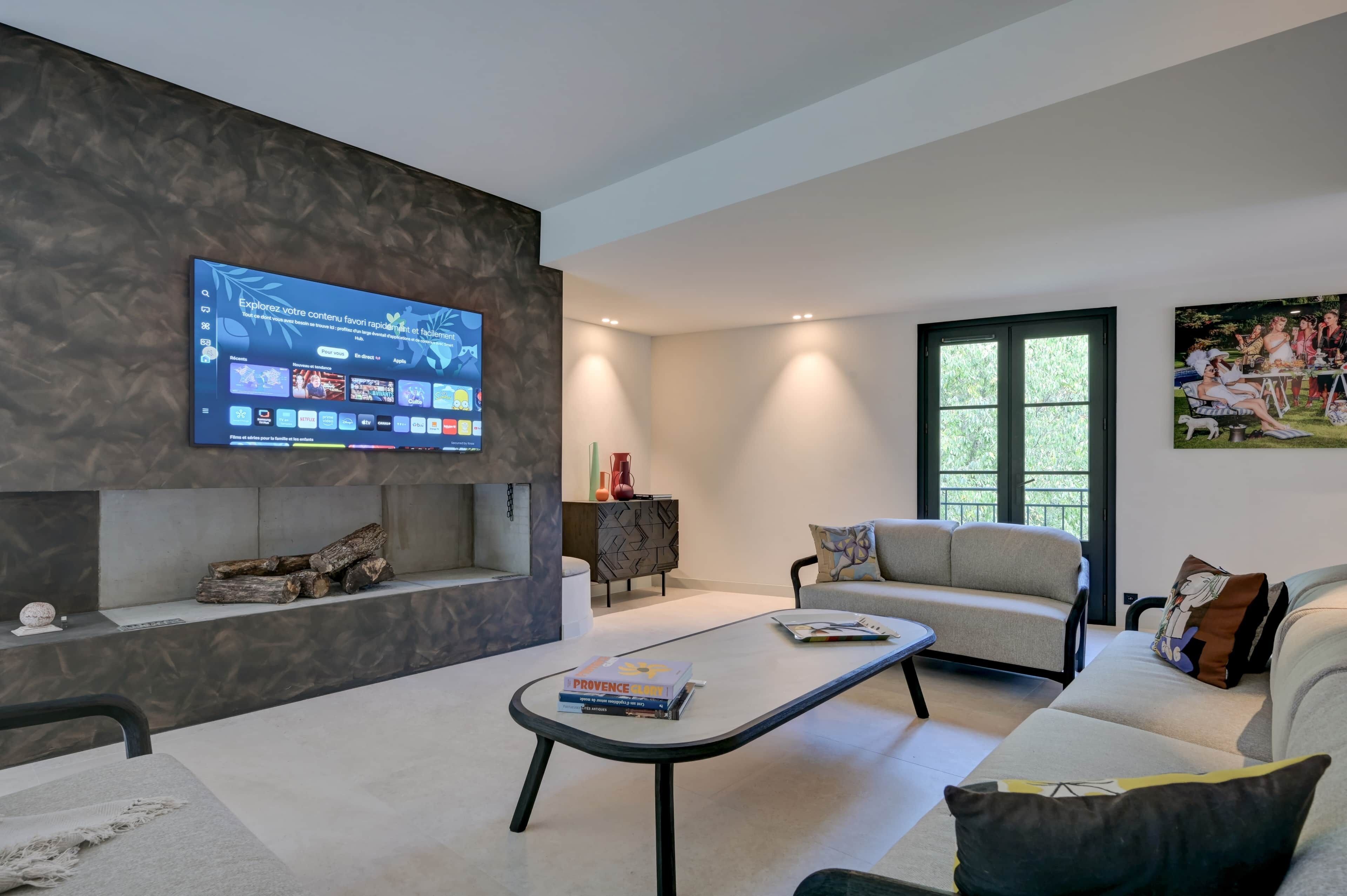 Un salon moderne avec un téléviseur à écran plat, un canapé, une table basse et une cheminée.