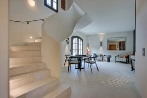 A modern interior with a spiral staircase, a dining area with a round table and chairs, and a seating area with a sofa and armchairs. - Provençal country house - Swimming pool - Sleeps 9 (Entrecasteaux)