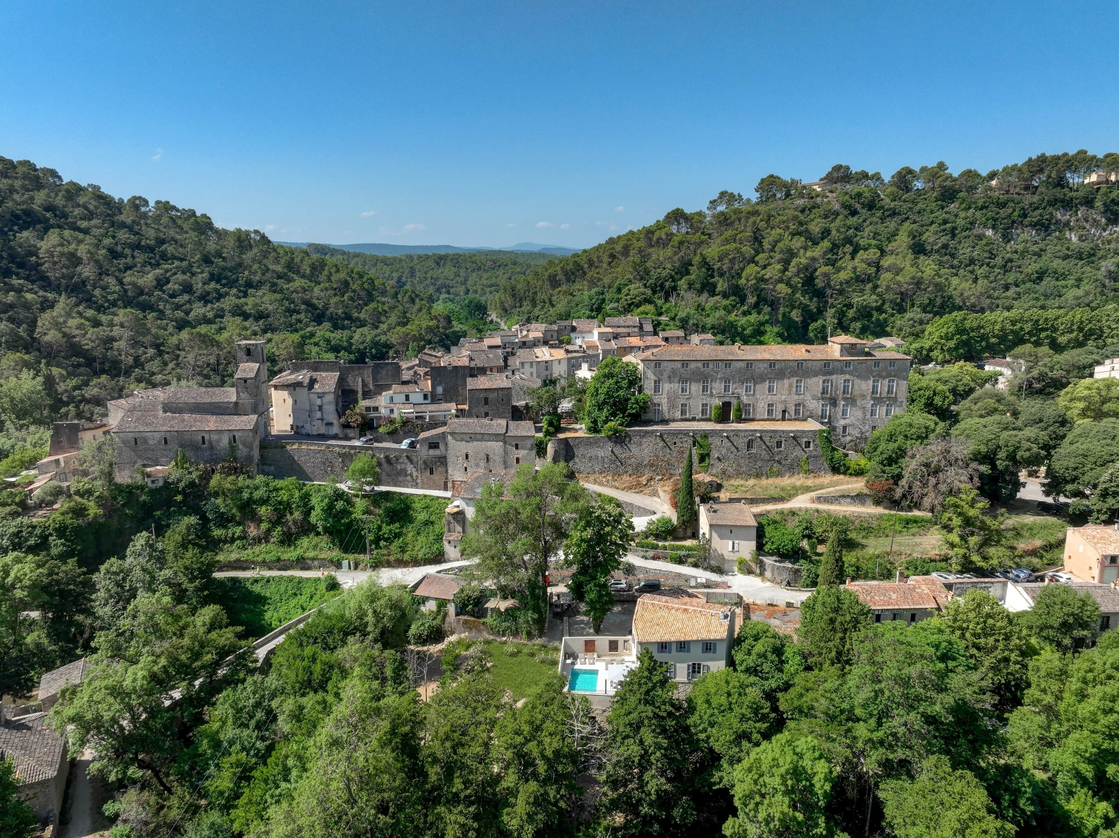 A historic town with stone buildings, a large central building, and a swimming pool.