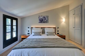 A bedroom with a large bed, a window with blinds, a wall-mounted light, and a cabinet. - Provençal country house - Swimming pool - Sleeps 9 (Entrecasteaux)