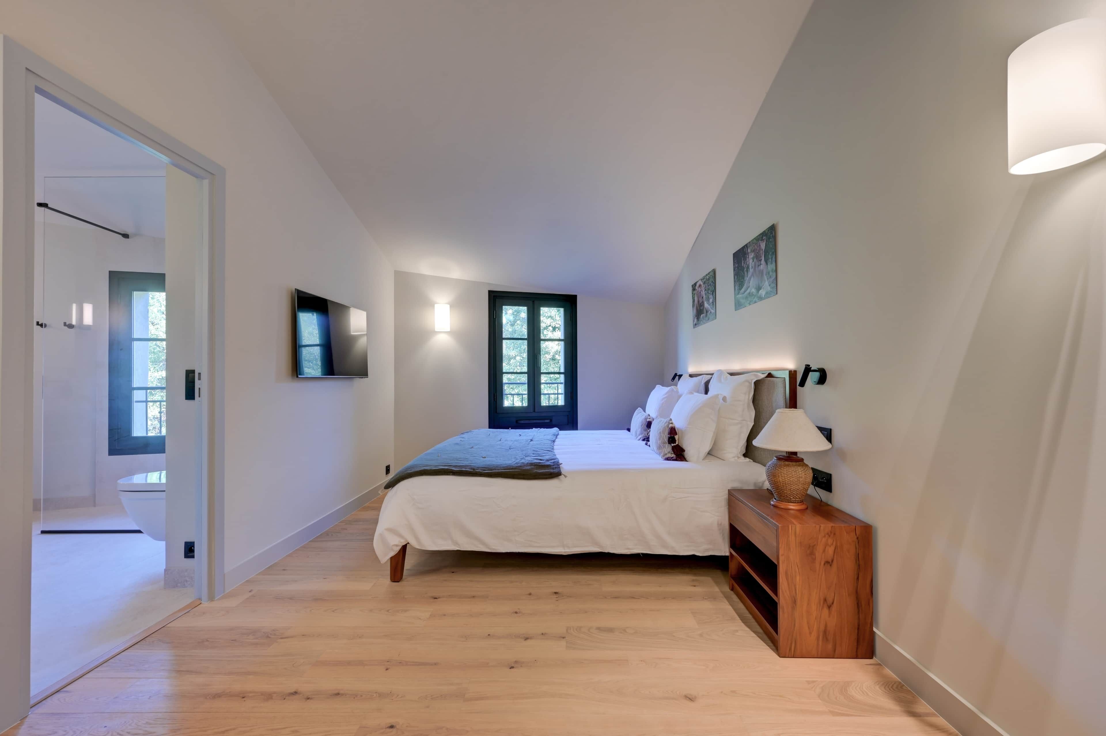 Une chambre à coucher avec un lit, une table de chevet, une lampe et une fenêtre.