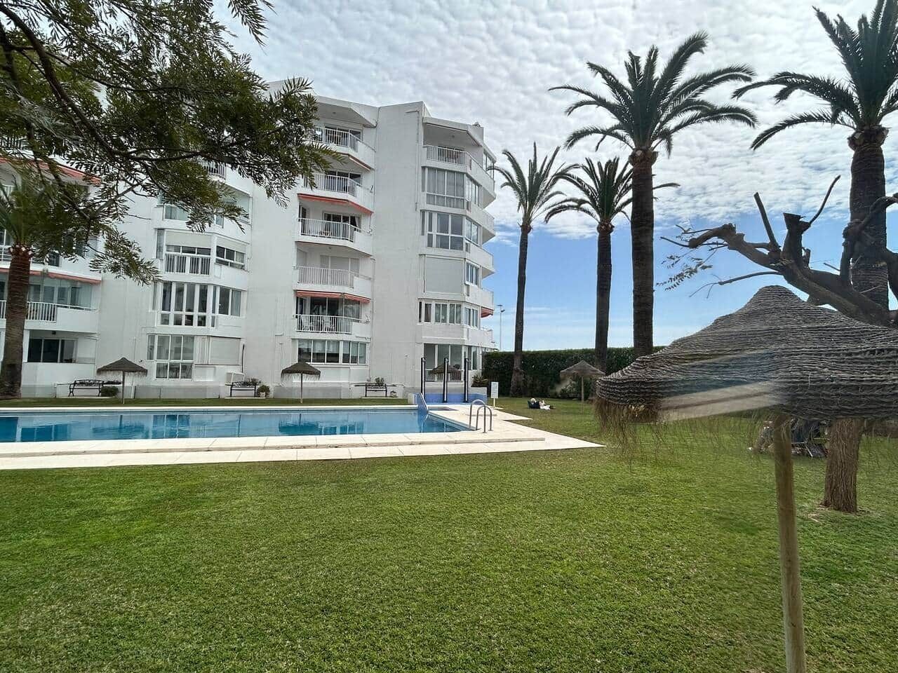 Ein modernes Hotel mit Pool, Palmen und einem strohgedeckten Gebäude.