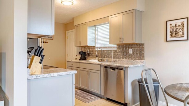 A compact kitchen with light-colored cabinets, a dishwasher, and a countertop with a coffee maker.