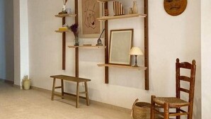 Ein Zimmer mit einer Holzbank, einem Stuhl und Regalen mit verschiedenen Dekorationsobjekten und einem gerahmten Bild.
