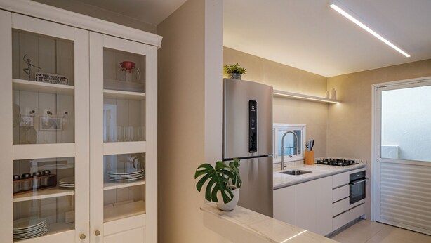 A modern kitchen with white cabinetry, a built-in oven, and a stainless steel refrigerator. - Casa em Jurerê com 4 quartos - 10 min da praia (Florianópolis)