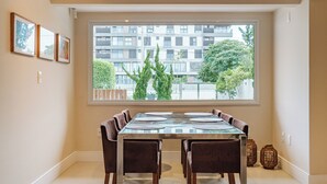 A dining area with a large window, a table set for six, and two chairs. - Casa em Jurerê com 4 quartos - 10 min da praia (Florianópolis)