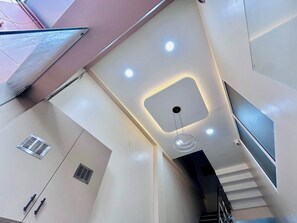 Un interior moderno con una escalera, iluminación empotrada en el techo y conductos de ventilación.
