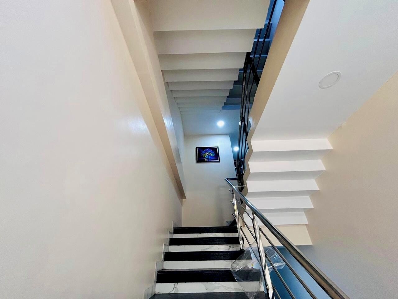 A modern staircase with a glass railing and a framed picture on the wall.
