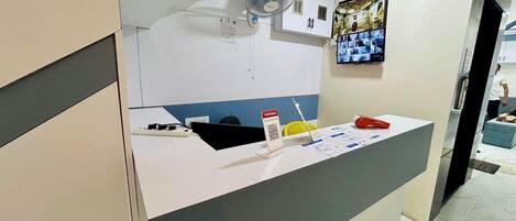 A reception desk with a computer, a fan, and informational brochures.