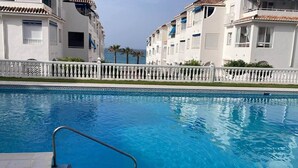 A swimming pool with steps leading into it, surrounded by white buildings with balconies and a white fence. - Fuentes de Nerja C 2F (Nerja)