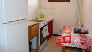A compact kitchen with a refrigerator, sink, oven, and a table with a red and white tablecloth. - 6-person apartment 50 m from the slopes, ideal for enjoying the mountains (VARS)