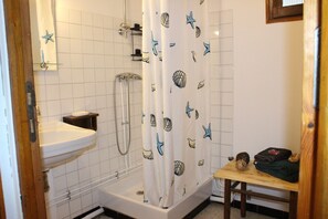Ein Badezimmer mit Dusche, Waschbecken und einem kleinen Tisch mit Handtüchern.