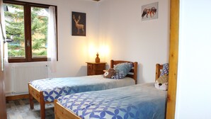 A bedroom with two wooden beds, a nightstand with a lamp, a window with curtains, and a radiator. - 6-person apartment 50 m from the slopes, ideal for enjoying the mountains (VARS)