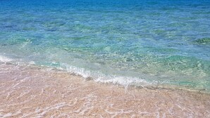 Une plage avec une eau claire et peu profonde et un rivage sablonneux.