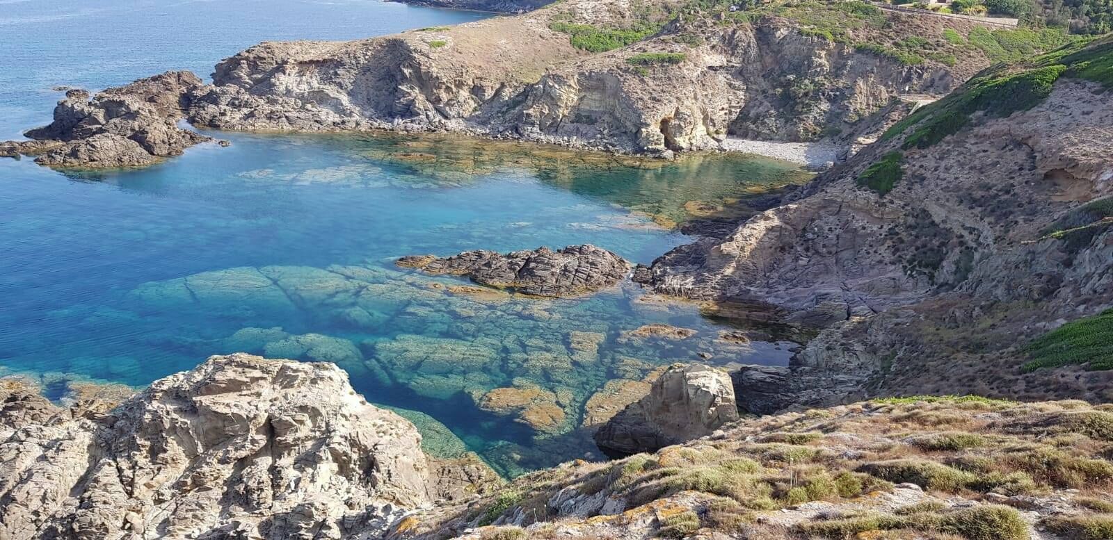 A coastal landscape with rocky terrain and clear blue waters.