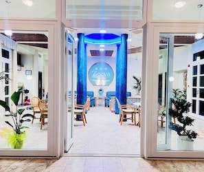 Un hall d’hôtel comprenant un comptoir d’accueil, un espace salon et une grande enseigne indiquant « Deeva Hotel & Resort ».