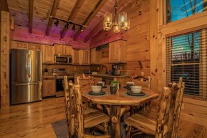 A rustic wooden interior with a dining table set for four, surrounded by wooden chairs. - Luxury Smoky Mountain Retreat | Views + Hot Tub (Sevier County)