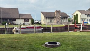 Une zone herbeuse avec une structure en béton, un petit étang et des maisons en arrière-plan.