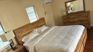 Une chambre à coucher avec un lit en bois, une table de chevet, une commode et un miroir.