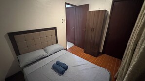 A bedroom with a bed, a wardrobe, and a door. - Cozy Clean Space with Balcony - Near Entrance (Davao City)